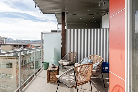Condo balcony with rattan chairs and a city view, Kelowna real estate photography