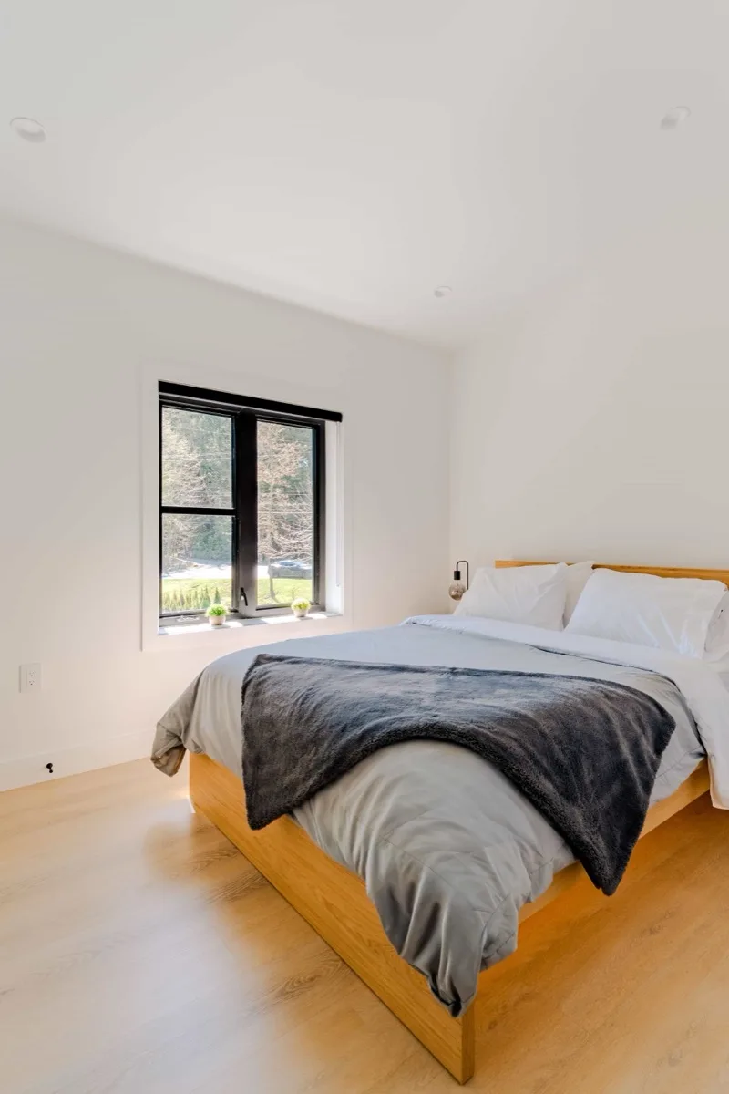 Master bedroom with wood-frame bed and natural light